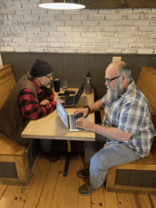 Michael and another person sitting in a booth working on laptops